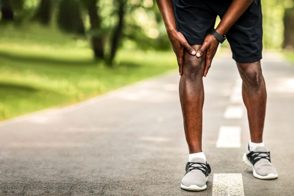 Closeup of black sportsman rubbing his sore knee