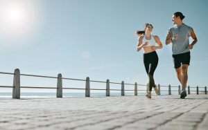 Couple, fitness and running by beach on mockup for exercise, workout or cardio routine together. Happy man and woman runner taking a walk or jog for healthy wellness or exercising